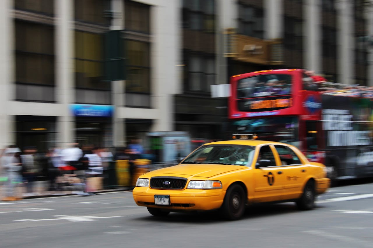 A yellow taxi speeds through the vibrant streets of New York City, capturing urban life and motion.